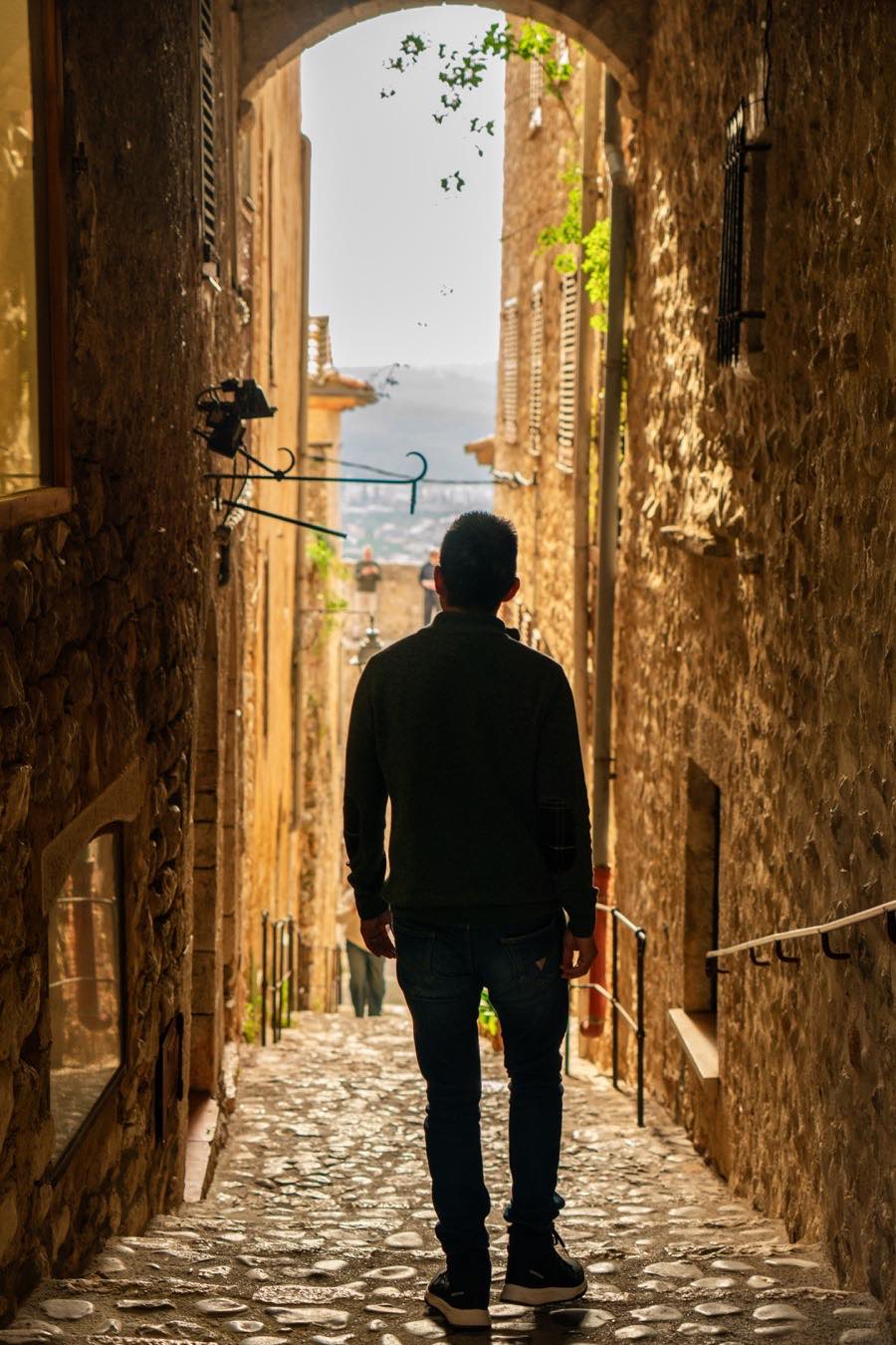 Laurence Tham walking down a cobbled lane in an old European town.